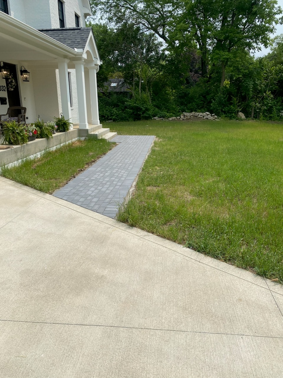 Gray paver front walkway leading to white home by Mark Monnette Masonry